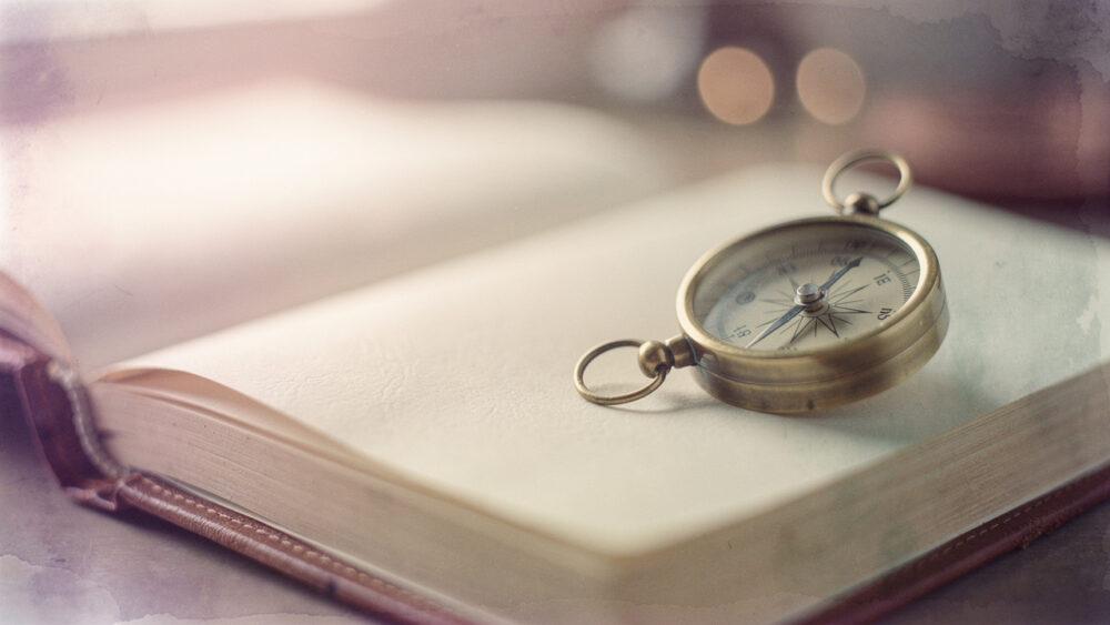 Compass resting on an open book, symbolizing guidance for AI citation optimized web content.