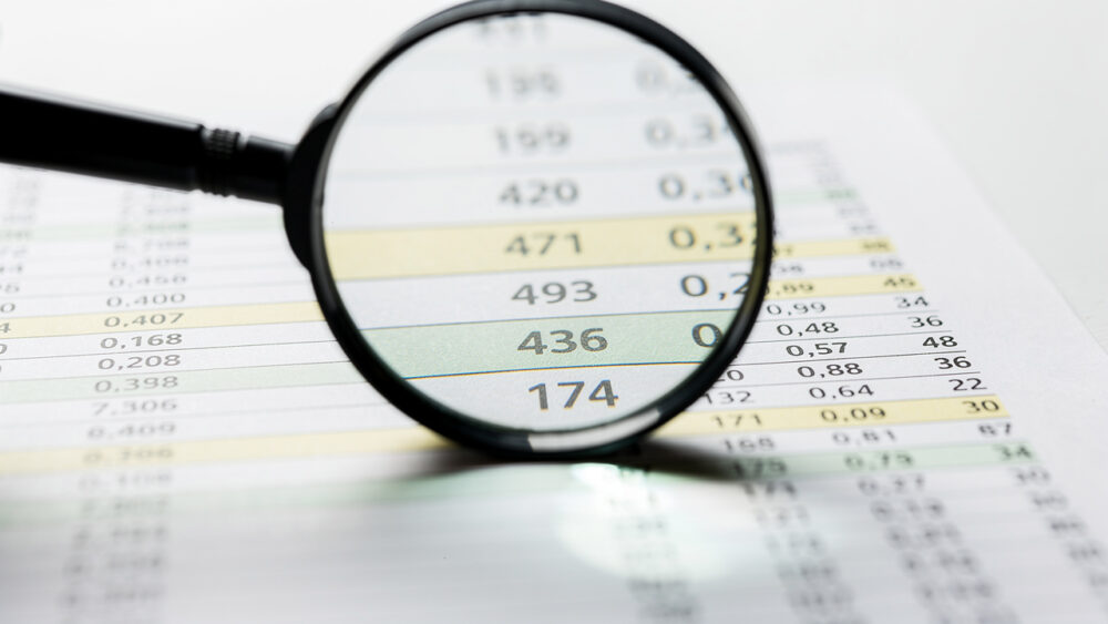 Magnifying glass over a spreadsheet with numbers, highlighting "436." Data analysis for SEO audit.